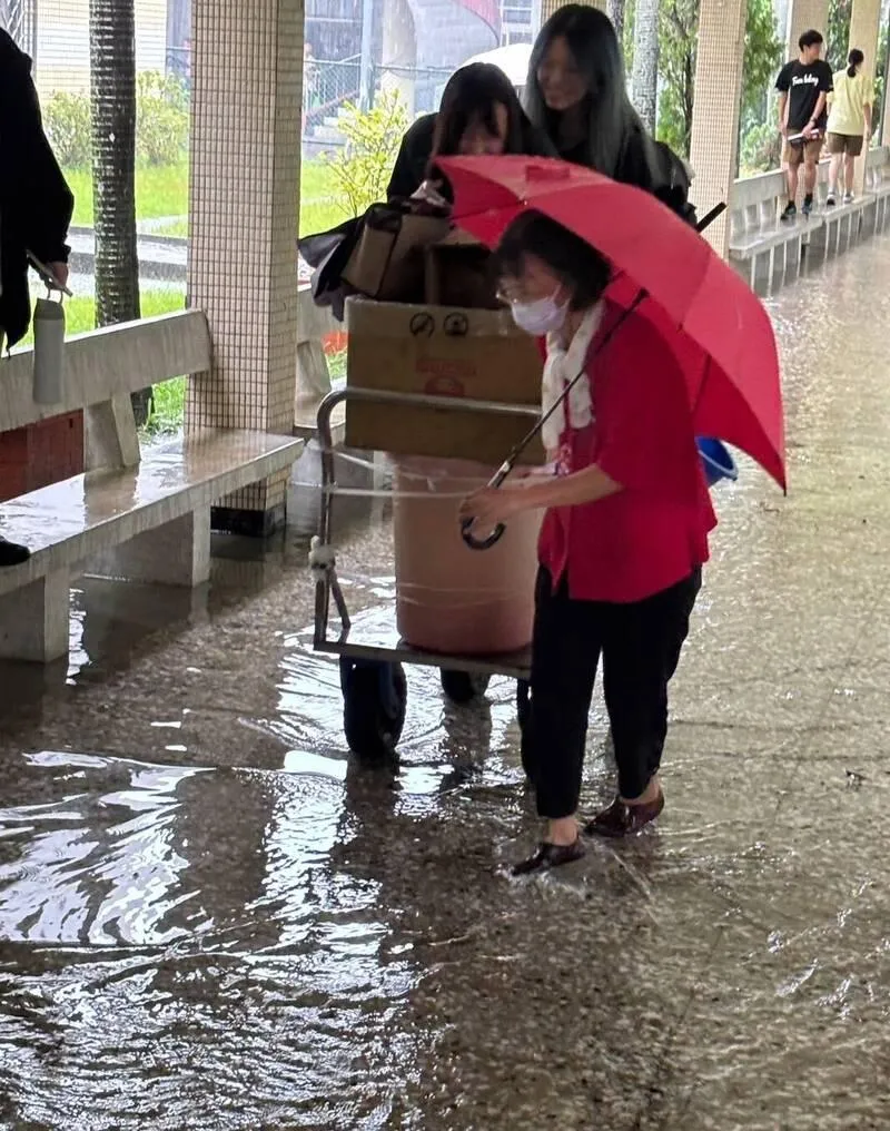 國立羅東高中校園重要通道風雨走廊因暴雨積水達30公分深，學生為了通行被迫脫掉鞋襪赤腳涉水，或改走兩側座椅避開淹水區域。（圖／羅東高中提供）