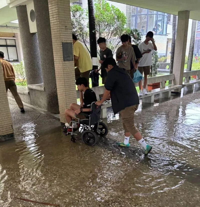 國立羅東高中校園重要通道風雨走廊因暴雨積水達30公分深，學生為了通行被迫脫掉鞋襪赤腳涉水，或改走兩側座椅避開淹水區域。（圖／羅東高中提供）