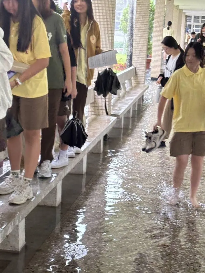 國立羅東高中校園重要通道風雨走廊因暴雨積水達30公分深，學生為了通行被迫脫掉鞋襪赤腳涉水，或改走兩側座椅避開淹水區域。（圖／羅東高中提供）