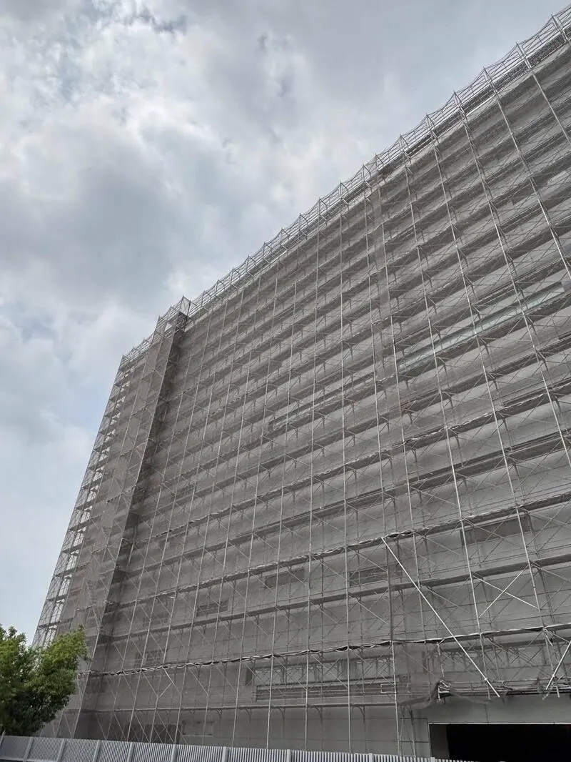 高雄市立殯儀館附近1棟民間殯葬業者的大樓工地,民眾目擊工人在高空鷹架作業時未做安全帶防護。(圖/高雄市勞工局提供)