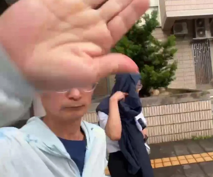 邱姓副院長一出法院在友人護駕下，用外套遮臉倉皇落跑。（圖／中天新聞）