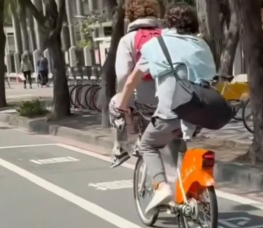 高雄2男子共乘YouBike，，其中1人坐在置物籃上，危險畫面曝光引起討論。（圖／翻攝自社會事新聞影音）