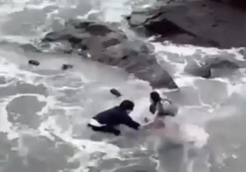 情侶兩人雙雙在海水中爬不起身。（圖／翻攝百姓關注）