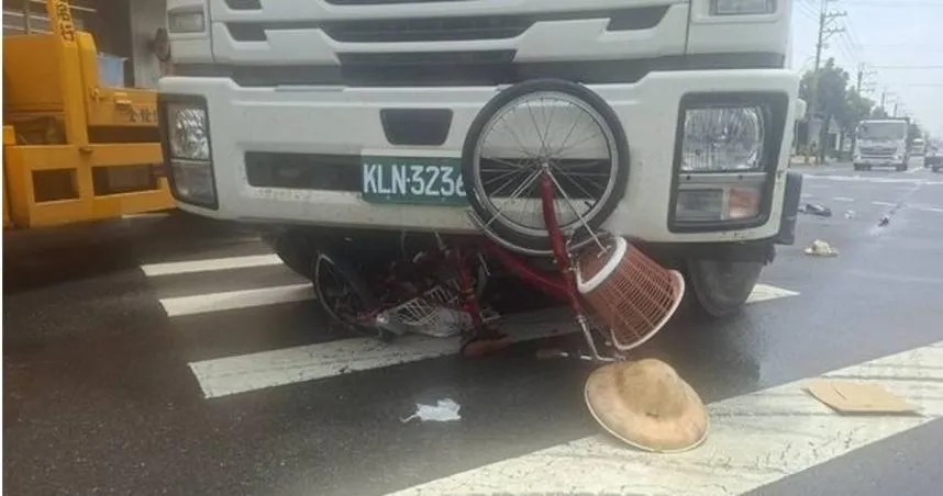 高雄大貨車擦撞腳踏車，老翁被困車底驚險救援，他帶的斗笠掉落一旁。（圖 ／中天新聞）
