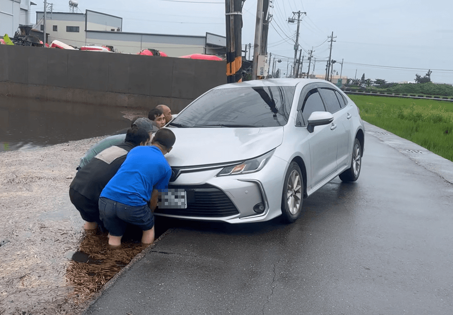 影/有你真好！伸港淹水「轎車陷水田」　工廠老闆率移工抬車