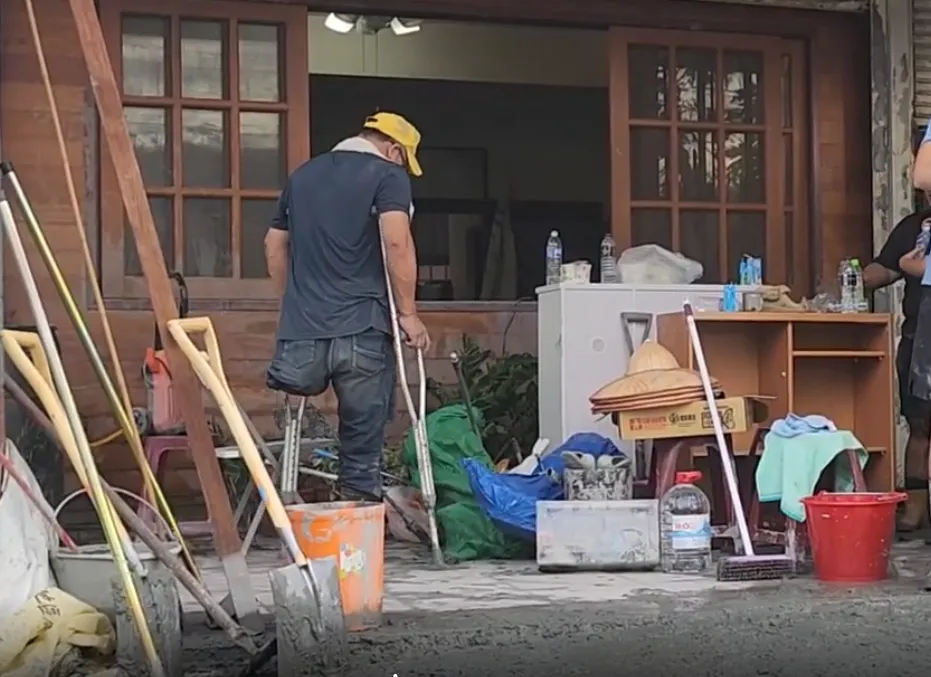 一名在光復經營書店的60歲老闆，左腳因工殘疾，僅靠一支拐杖帶頭清理滿屋淤泥。（圖／中天新聞，下同）