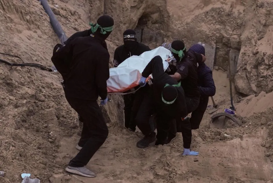 哈瑪斯戰士從地道中出現,抬著一具以白色塑膠袋包裹的遺體。(圖/美聯社)