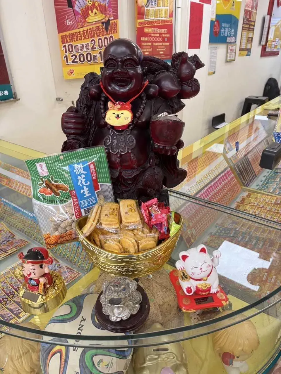 兩位幸運兒都在刮中大獎的隔天帶著花生和鳳梨酥回到彩券行,供奉在彌勒佛像前,感謝神明庇佑。(圖/台彩提供)