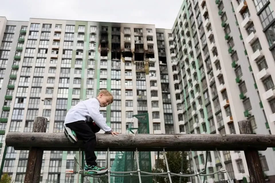 烏克蘭基輔一名孩童在被俄羅斯無人機襲擊的公寓前玩耍。（圖／路透社）